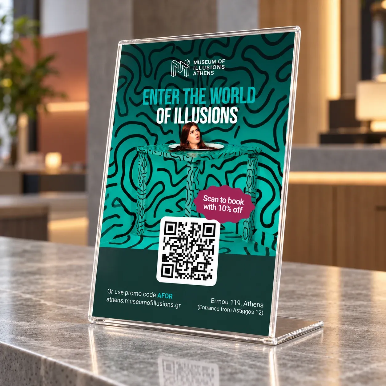 An acrylic counter stand with the Museum of Illusions key visual and a QR code to book with 10% off